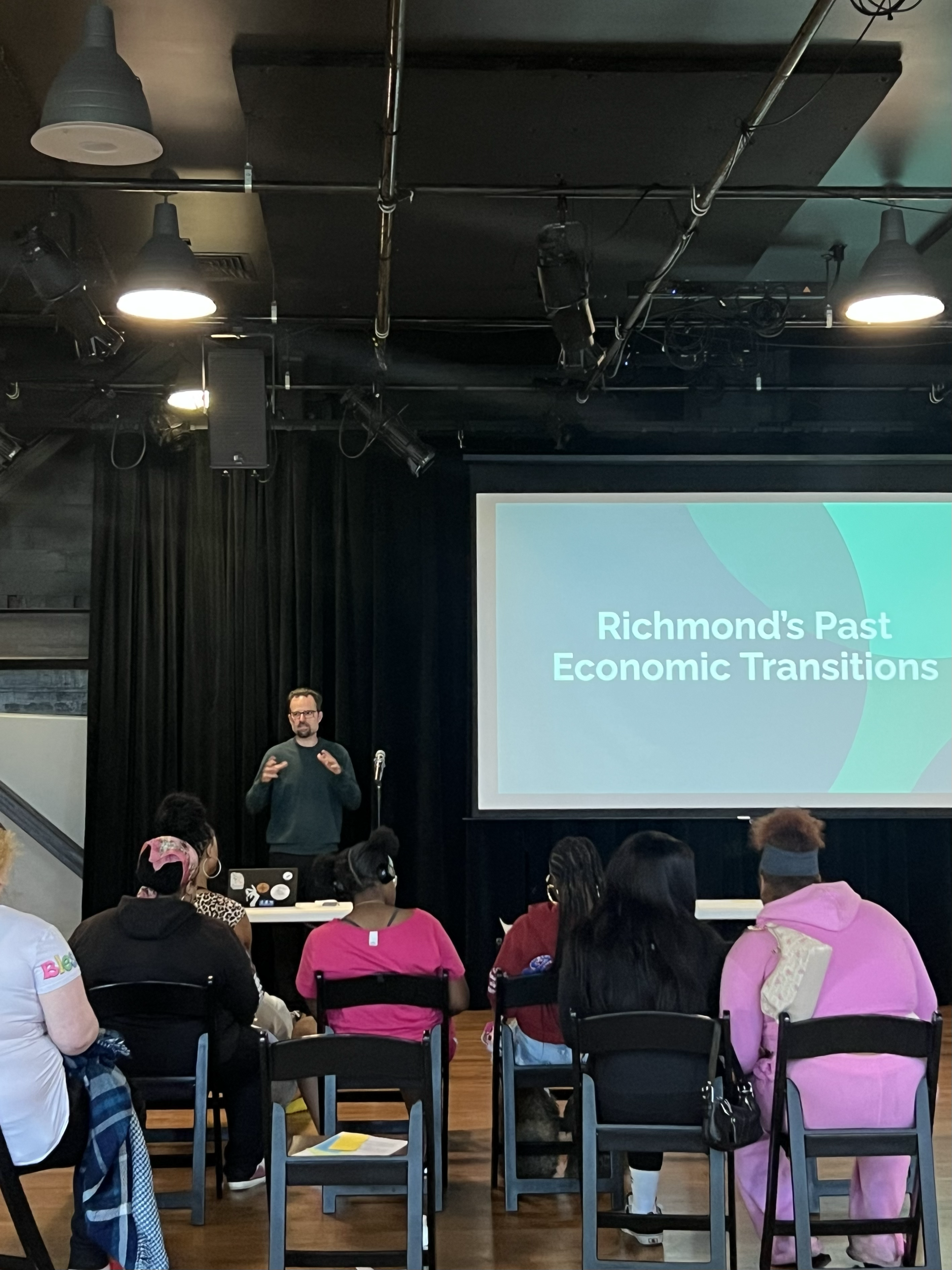 Eli Moore presenting at a community workshop, with a slide reading 'Richmond's Past Economic Transitions.'
