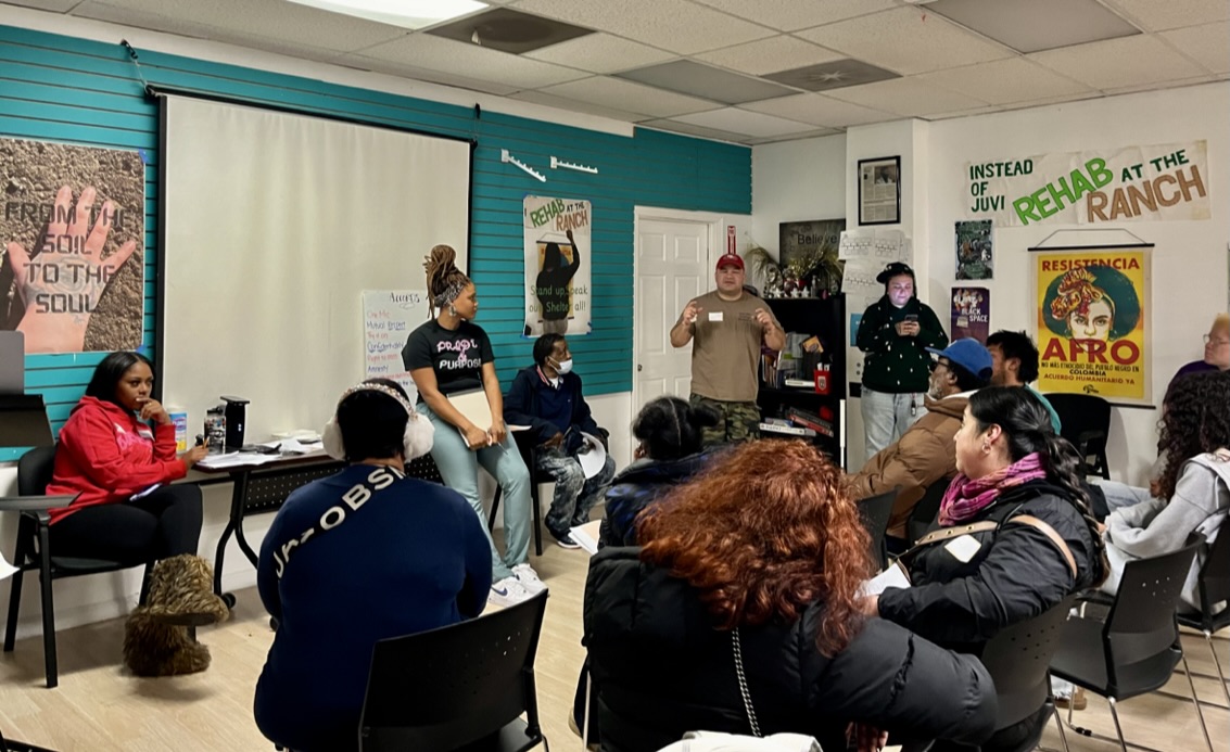 A Safe Return Project workshop session with community members seated in a circle.